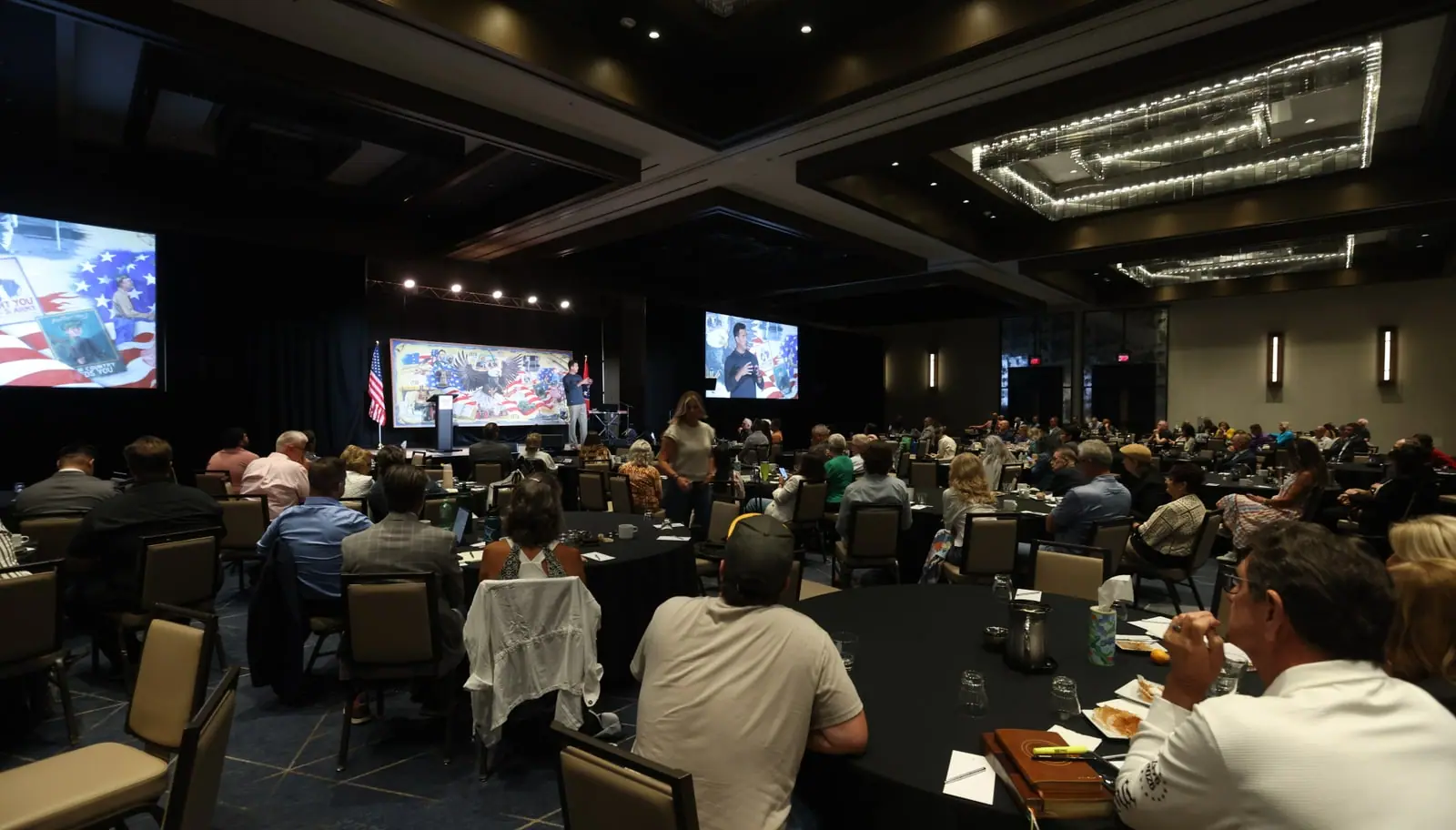 Ignite attendees seated around tables while a speaker addresses the gathering